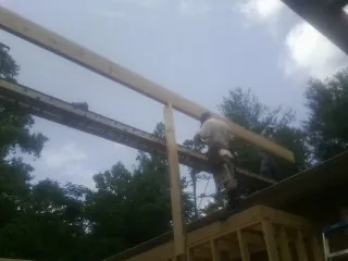 Carpenter setting a ridge beam over a new addition frame — Ice Dam Removal by Roofing Brothers in Solon