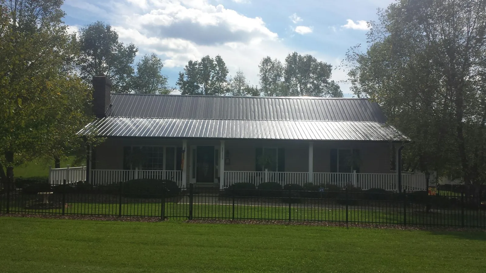 Gray metal roof on a brick ranch with a full width front porch — Gutter Guard Installation work by our crew in Solon